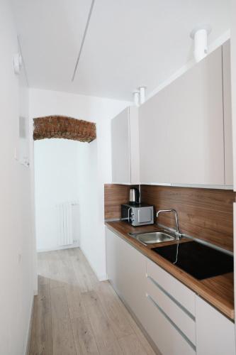 a kitchen with white cabinets and a sink at Como Charm Living Apartment Duomo in Como