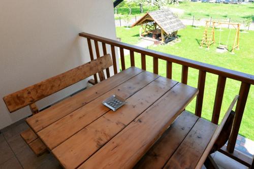a wooden table and bench on a balcony with a playground at Žemyna Apartmentai in Druskininkai