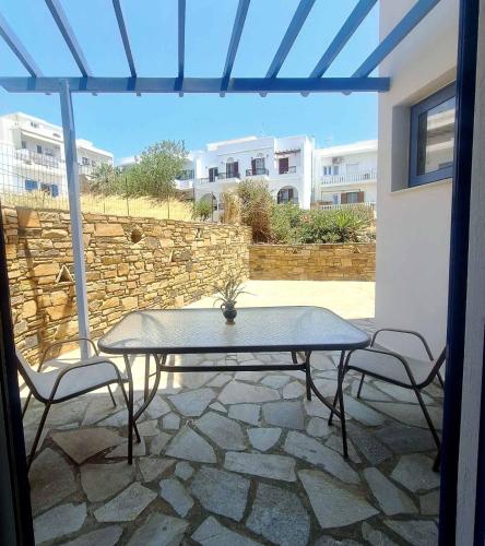 a patio with a table and two chairs and a stone wall at Athos Studios in Tinos Town