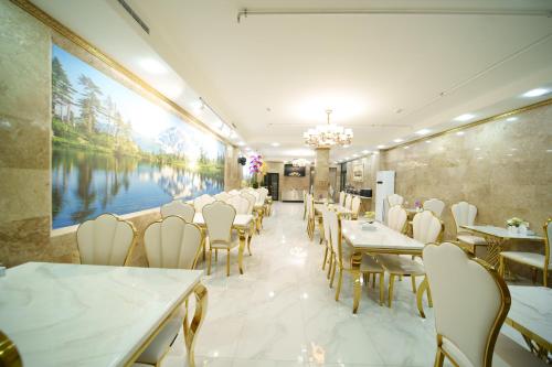 a restaurant with tables and chairs and a large painting on the wall at Emmanuel Hotel Yerevan in Yerevan