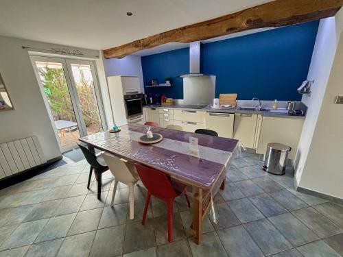 une cuisine avec une table et des chaises et un mur bleu dans l'établissement Maison indépendante, domaine VICHY LA TOUR, à Abrest