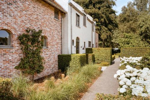 a brick house with white flowers in front of it at B&B Interludium in Nijlen