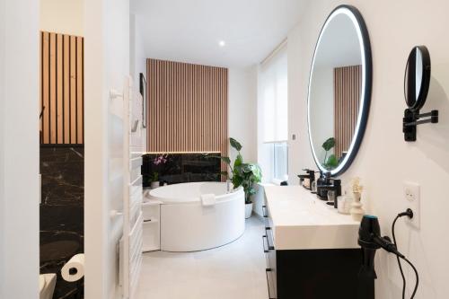 a white bathroom with a large mirror and a tub at La Suite H in Metz