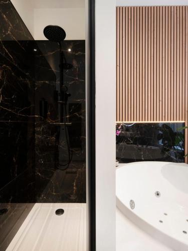 a bathtub in a bathroom with a black wall at La Suite H in Metz