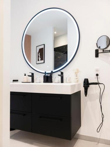 a bathroom with a black vanity and a round mirror at La Suite H in Metz