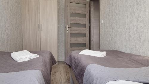 a bedroom with two beds and a closet at Q Apart PL 2 lub 3 pokojowe klimatyzowane apartamenty przy Manufakturze z garażem Gratis, FV in Łódź