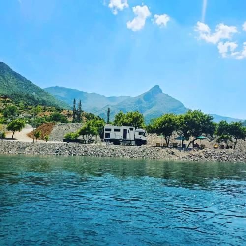 an rv parked on the side of a river at I Love Koman Camping in Shkodër