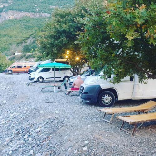 a couple of people sitting under an umbrella next to a van at I Love Koman Camping in Shkodër