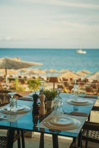 a blue table with plates and glasses on the beach at Ionion Beach Resort in Parga
