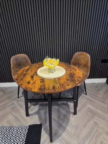a wooden table with two chairs and a vase on it at Courtyard High Spec Apartment in Town Centre in Blackburn