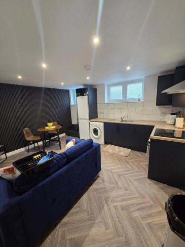 a living room with a blue couch and a kitchen at Courtyard High Spec Apartment in Town Centre in Blackburn