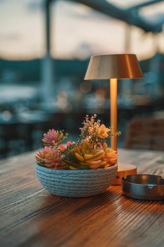 a flower arrangement in a bowl on a table with a lamp at Ionion Beach Resort in Parga