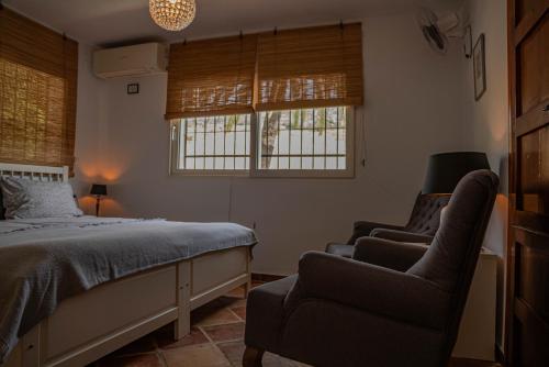 a bedroom with a bed and a chair and windows at El bufon de la corte in Carratraca