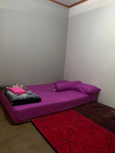 a small purple bed in a corner of a room at Reronggak cafe and homestay in Sembalun Lawang