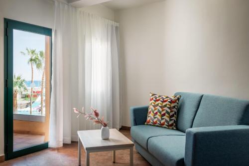 a living room with a blue couch and a table at ALEGRIA Colonial Mar Aquafun in Roquetas de Mar