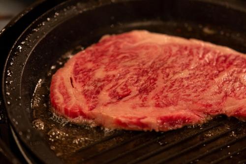 a piece of meat cooking in a pan at Pension Balmy in Nasu