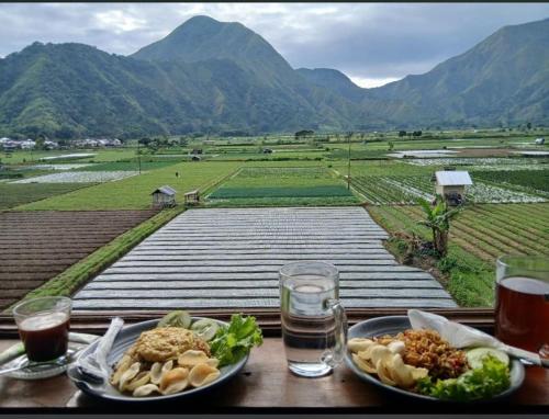 a table with two plates of food and a view of mountains at Reronggak cafe and homestay in Sembalun Lawang
