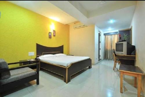 a bedroom with a bed and a couch and a tv at Vinttage park hotels in Bengaluru
