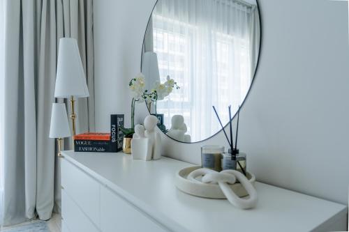 a white dressing table with a mirror and flowers on it at Nasma Luxury Stays - Sky-High Serenity in Stylish 2BR Retreat in Dubai