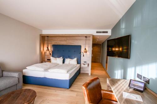 ein Schlafzimmer mit einem Bett, einer Couch und einem Tisch in der Unterkunft Pfalzblick Wald Spa Resort in Dahn