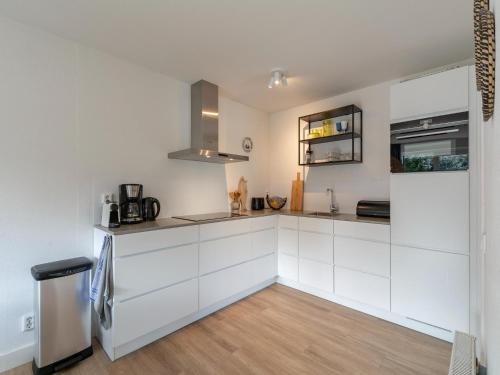 a kitchen with white cabinets and a refrigerator at Villa in Julianadorp near the Beach in Julianadorp