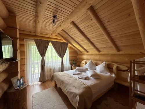 a bedroom with a bed in a wooden room at Chalet in Muntii Vrancei - Gresu - Lepsa cu Ciubar si Sauna in Greşu