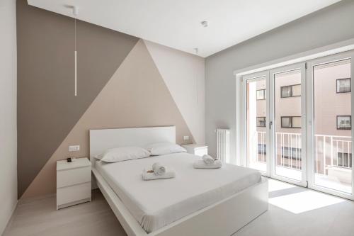 une chambre blanche avec un lit et une grande fenêtre dans l'établissement Vatican Suites, à Rome