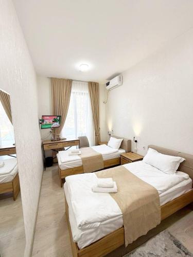 a hotel room with three beds and a desk at SADI Hotel in Yakkasaray
