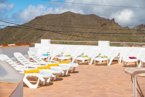 a row of white chairs sitting on top of a roof at sunset lodge in Las Manchas