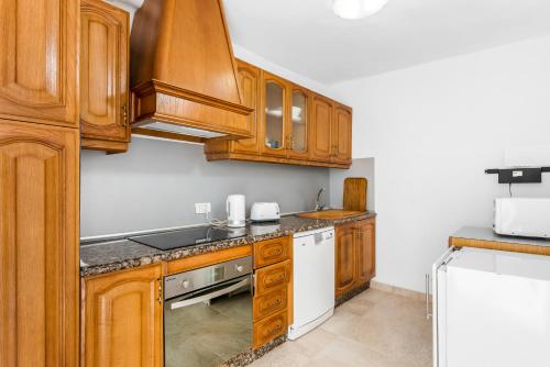 a kitchen with wooden cabinets and a white appliance at sunset lodge in Las Manchas