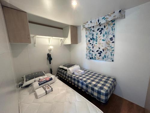 une petite pièce avec un lit et une fenêtre dans l'établissement Mobil-home camping 4 étoiles, à Cancale