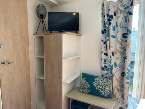 Cette chambre dispose d'une télévision sur une étagère et d'une fenêtre. dans l'établissement Mobil-home camping 4 étoiles, à Cancale