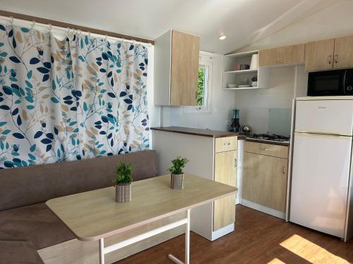 une cuisine avec une table et un réfrigérateur blanc dans l'établissement Mobil-home camping 4 étoiles, à Cancale