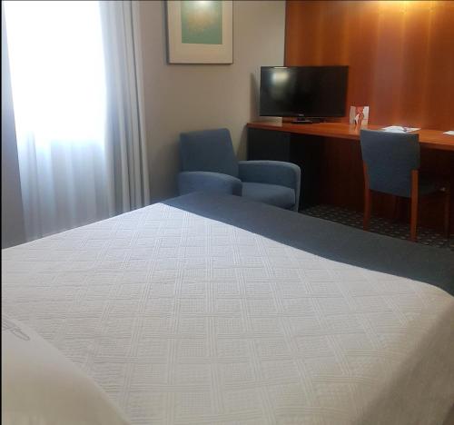 a room with a bed and a desk and a television at Gran Hotel Albacete in Albacete