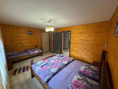 a bedroom with two beds and wooden walls at Садиба у Софійки in Synevyrsʼka Polyana