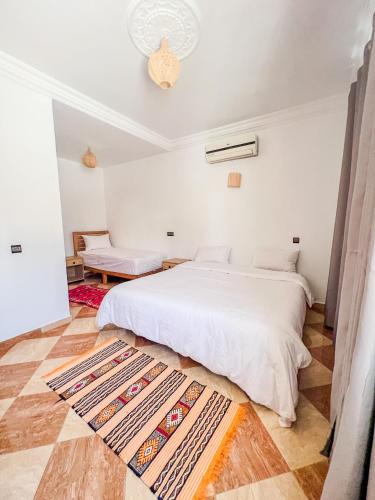 a white bedroom with a bed and a rug at Dar Surfana Morocco in Aourir