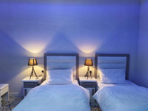 two beds in a room with two lamps on them at مرفق ضوء القمر السياحي بالباحة in Al Baha