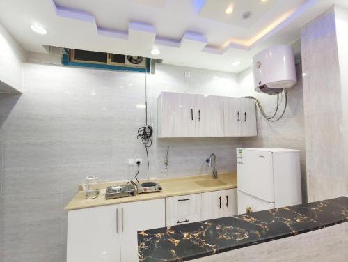 a kitchen with white cabinets and a white refrigerator at مرفق ضوء القمر السياحي بالباحة in Al Baha