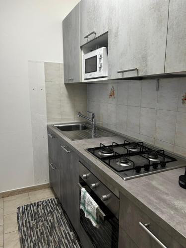 a kitchen with a stove and a sink and a microwave at BWR - Bilocale a Cornaredo ---vicino Rho Fiera--- in Cornaredo