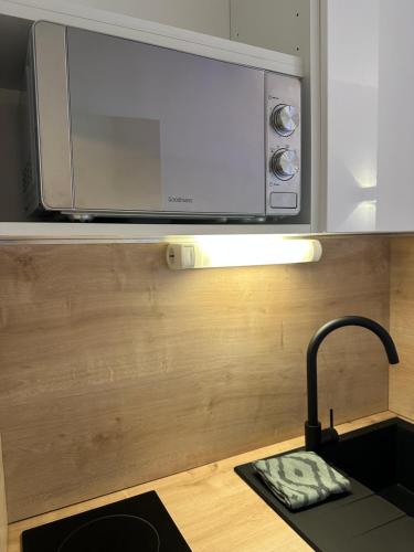 a microwave above a kitchen counter with a sink at Studio MBS 2- Cosy, Tramway, Wifi, Parking, Equipé in Montpellier