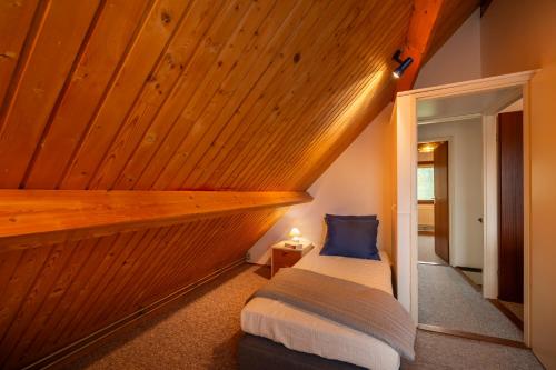 a bed in a room with a wooden ceiling at De Duiker in Wolphaartsdijk