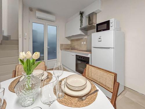 Il comprend une cuisine équipée d'une table avec des chaises et d'un réfrigérateur blanc. dans l'établissement Maison 10 min de Béziers, 30 min de la mer et sa terrasse panoramique, à Puissalicon