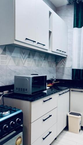 a kitchen with white cabinets and a microwave at Entire Furnished Apartment Unit in Kira in Kira