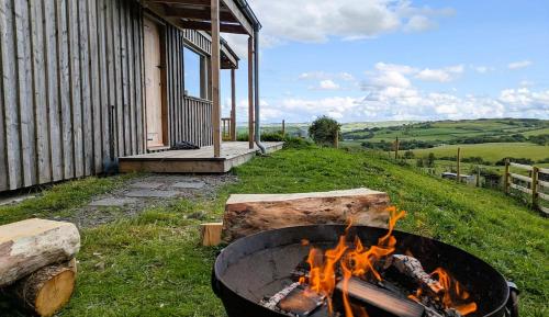a fire pit in front of a house at The Fold - Unique Cabin Nestled in Nature in Llangernyw