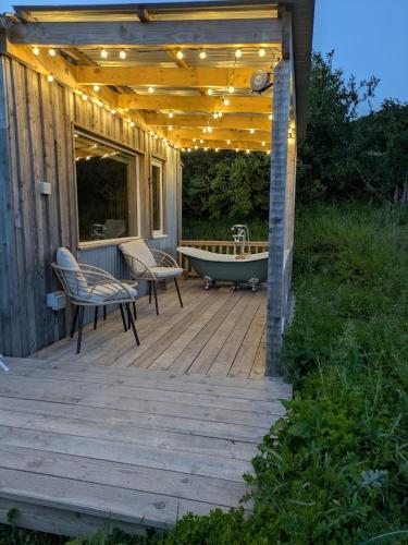 a deck with a tub and a bench and lights at The Fold - Unique Cabin Nestled in Nature in Llangernyw