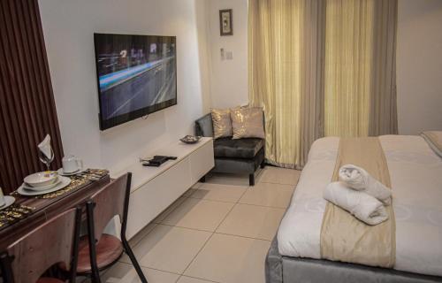 a hotel room with a bed and a television at Lovely studios at Embassy Gardens in Accra