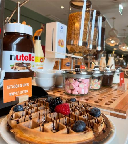 a waffle cake with chocolate and berries on a counter at Hampton By Hilton Malaga Martiricos in Málaga