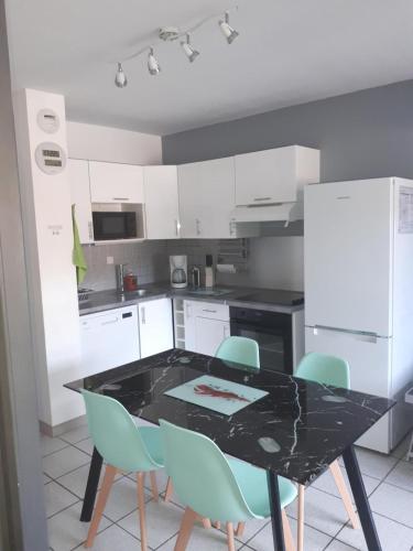 une cuisine avec une table noire et des chaises bleues dans l'établissement Joli et Spacieux Appartement, à Cerbère