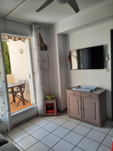 - un salon avec une télévision, une table et une porte dans l'établissement Joli et Spacieux Appartement, à Cerbère