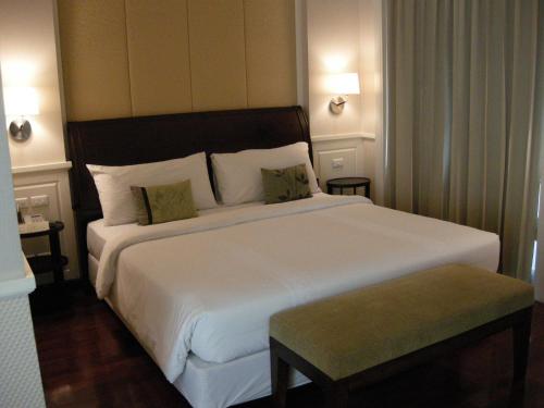 a bedroom with a large white bed and a green stool at Aurum The River Place in Bangkok